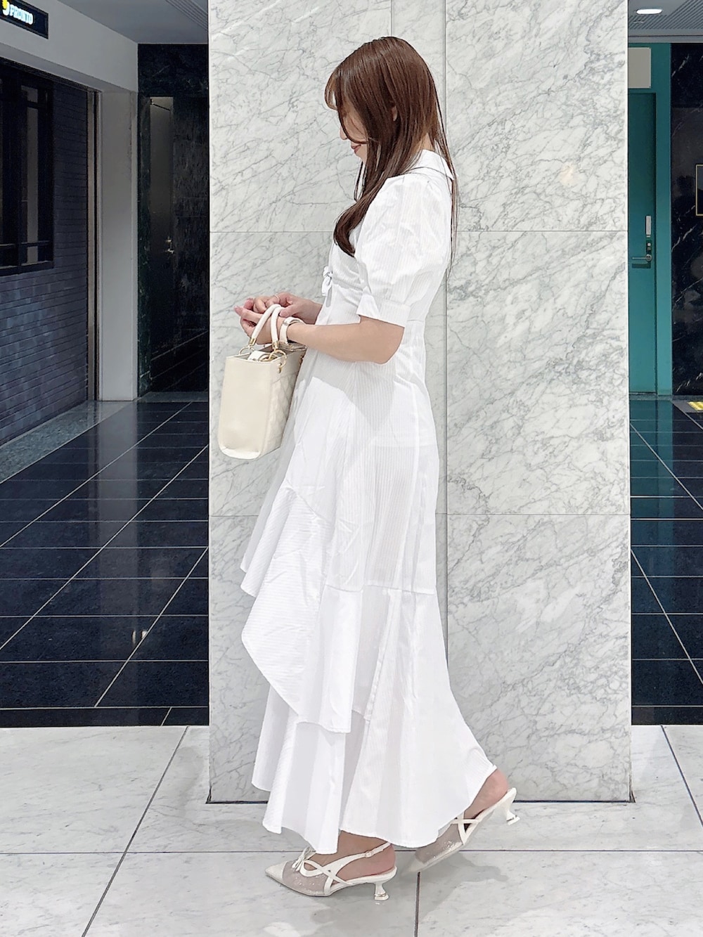 ホワイト系のワンピース、ホワイト系のパンプス、ホワイト系のハンドバッグを着用したレディースの春コーディネートの5枚目の写真