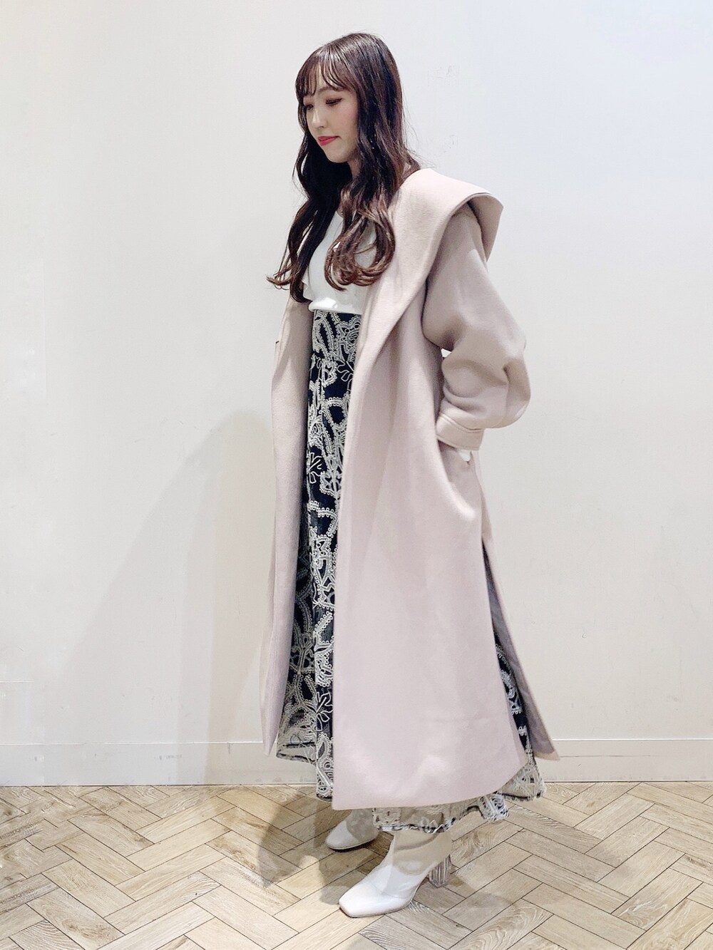 ブラック系のスカート、ホワイト系のニット/セーター、ベージュ系のチェスターコートを着用したレディースの冬コーディネートの2枚目の写真