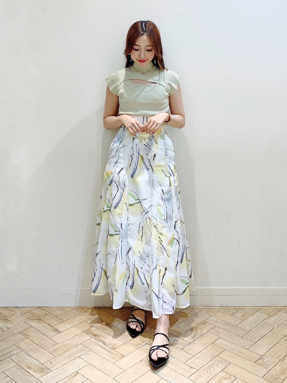 グリーン系のニット/セーター、イエロー系のスカート、ブラック系のサンダルを着用したレディースの夏コーディネートの2枚目の写真