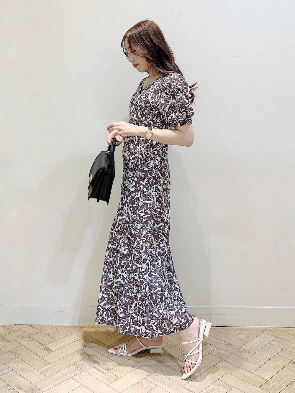 グレー系のワンピース、ホワイト系のサンダル、ブラック系のハンドバッグを着用したレディースの春コーディネートの4枚目の写真