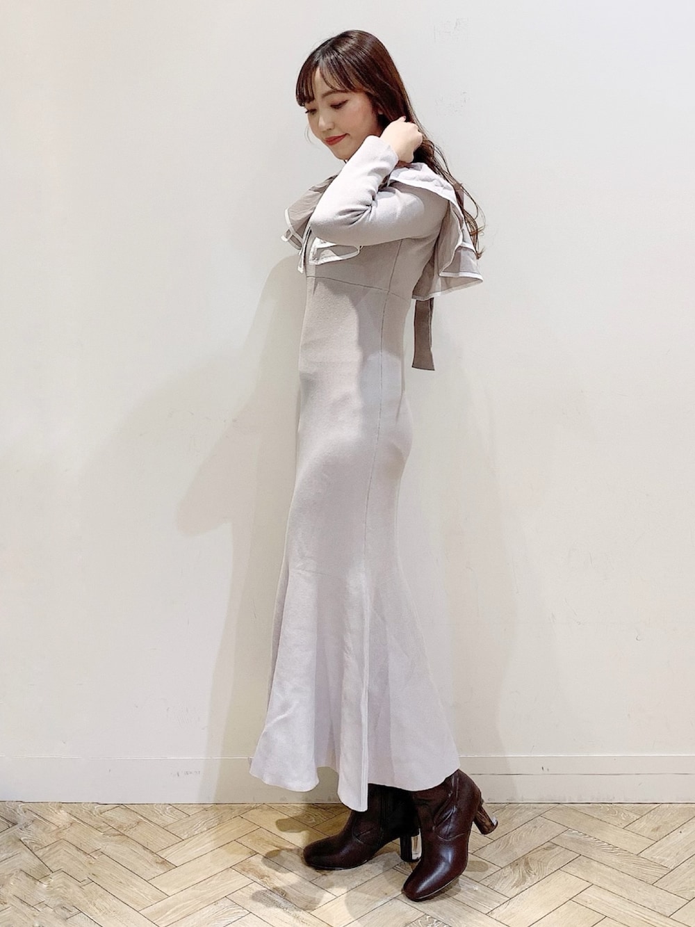 ベージュ系のワンピース、ホワイト系のチェスターコート、ブラウン系のブーツを着用したレディースの冬コーディネートの3枚目の写真