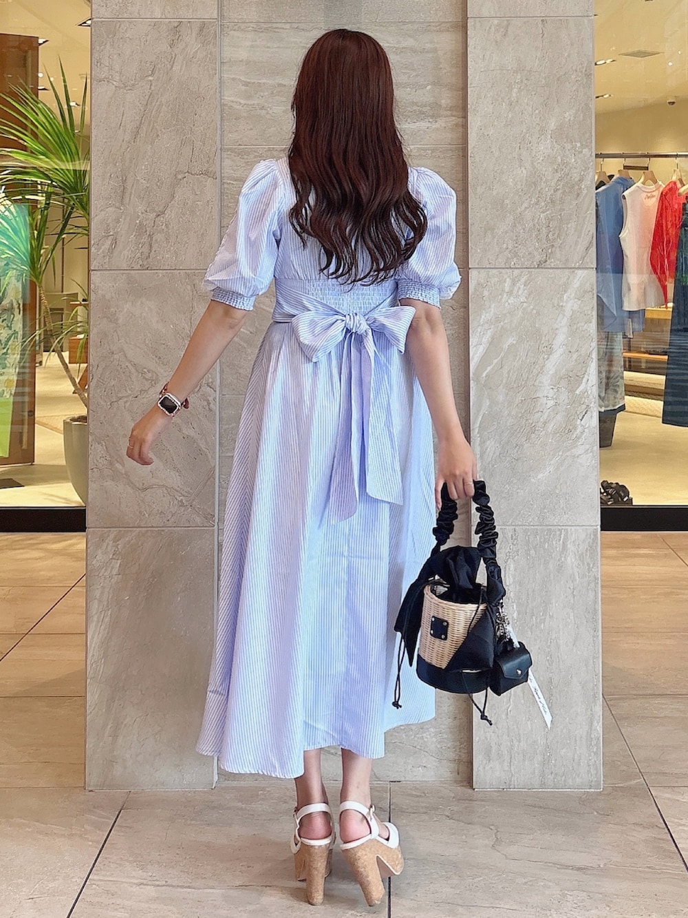 ブラック系のかごバッグ、ホワイト系のサンダル、ブルー系のワンピースを着用したレディースの夏コーディネートの5枚目の写真