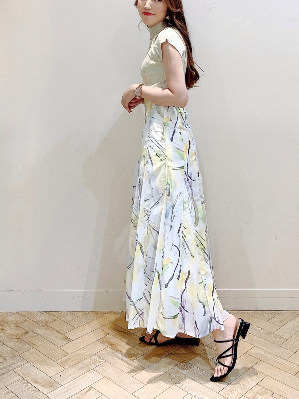 グリーン系のニット/セーター、イエロー系のスカート、ブラック系のサンダルを着用したレディースの夏コーディネートの3枚目の写真