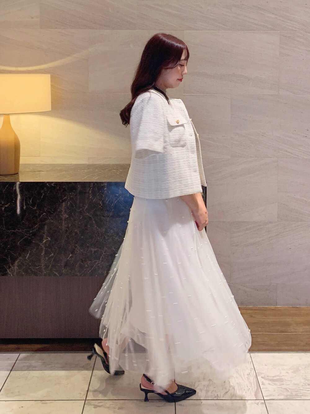 ホワイト系のスカート、ホワイト系のノーカラージャケット、ベージュ系のニット/セーターを着用したレディースの夏コーディネートの5枚目の写真