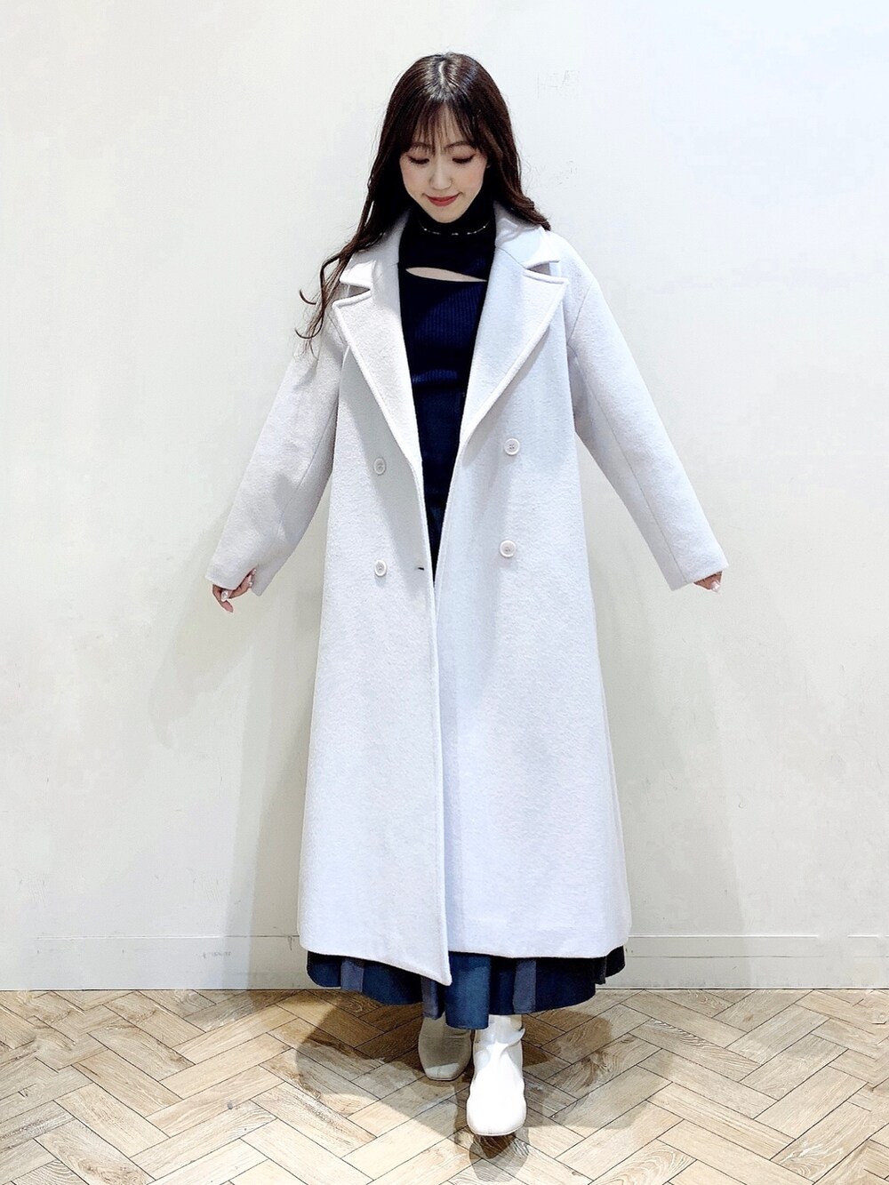 グレー系のニット/セーター、グレー系のスカート、ホワイト系のブーツを着用したレディースの冬コーディネートの6枚目の写真