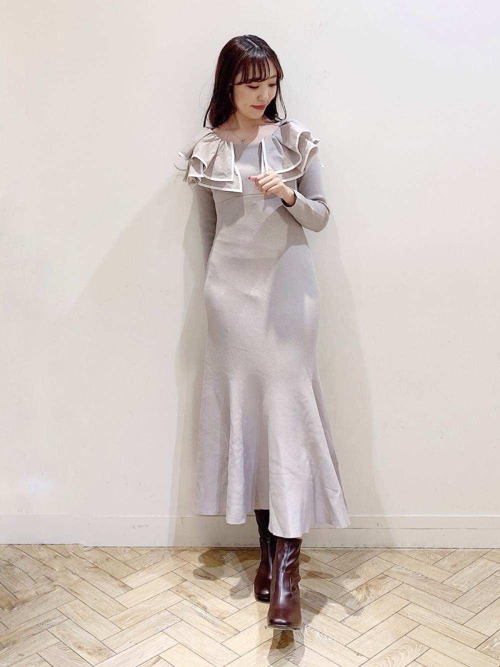 ベージュ系のワンピース、ホワイト系のチェスターコート、ブラウン系のブーツを着用したレディースの冬コーディネートの2枚目の写真