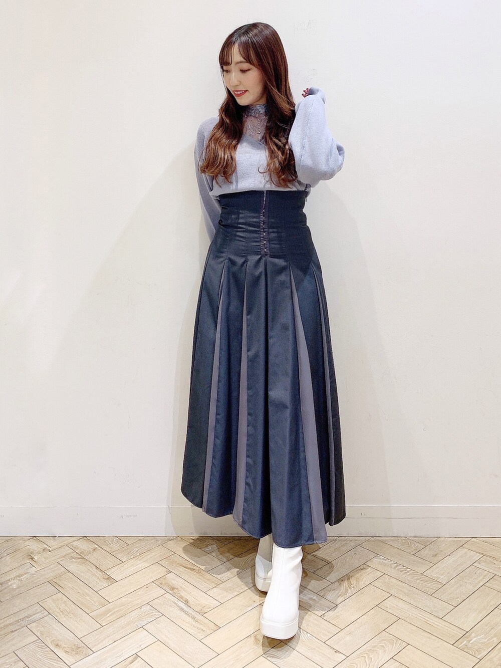 グレー系のスカート、ブルー系のニット/セーター、ホワイト系のブーツを着用したレディースの秋コーディネートの3枚目の写真