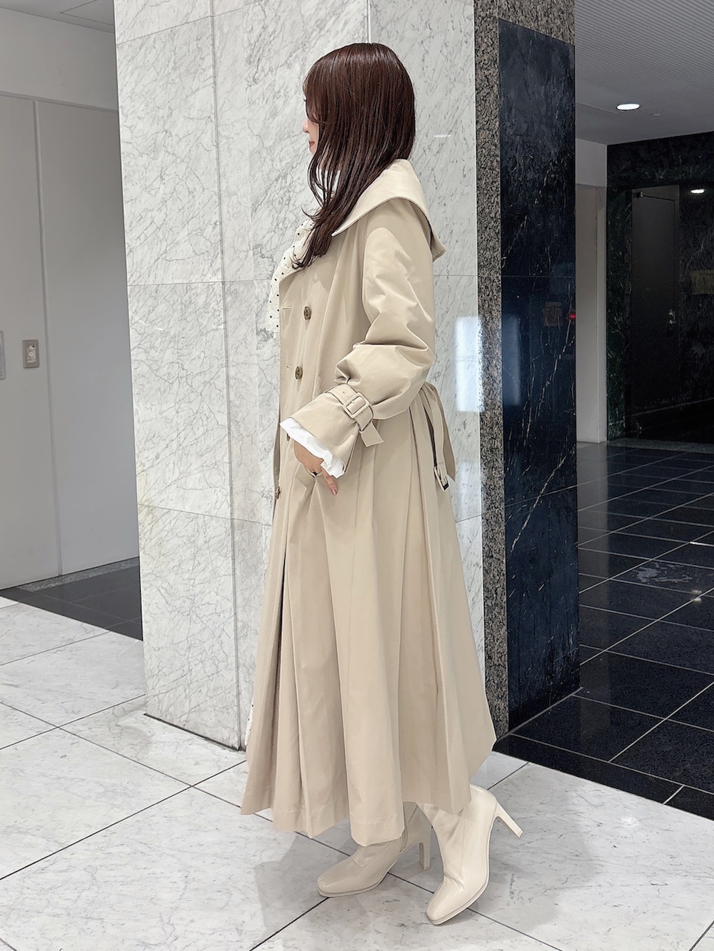 ホワイト系のブーツ、ベージュ系のトレンチコート、ホワイト系のワンピースを着用したレディースの冬コーディネートの7枚目の写真
