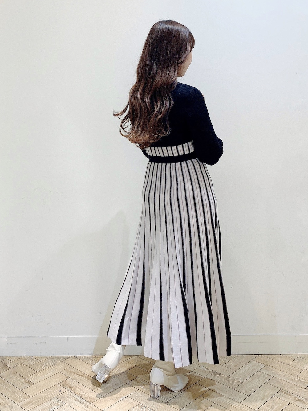 ブラック系のワンピース、ホワイト系のムートンコート、ホワイト系のブーツを着用したレディースの冬コーディネートの4枚目の写真