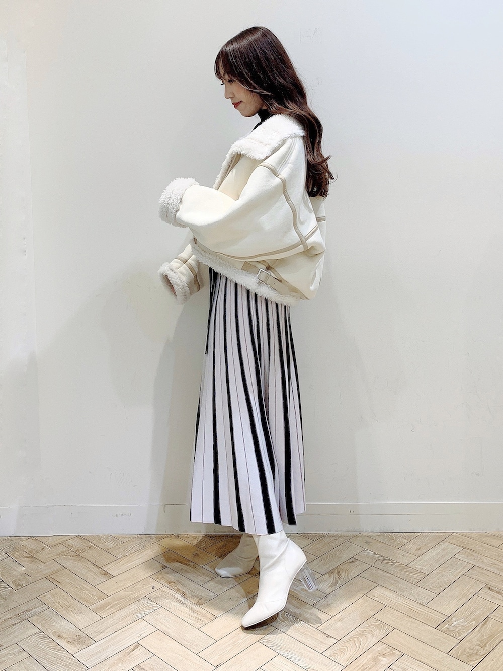 ブラック系のワンピース、ホワイト系のムートンコート、ホワイト系のブーツを着用したレディースの冬コーディネートの6枚目の写真