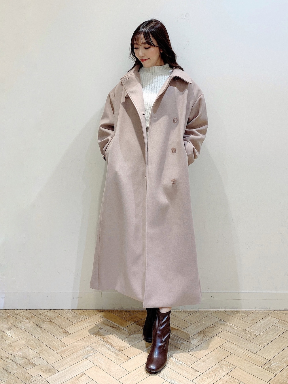 ホワイト系のワンピース、ベージュ系のステンカラーコート、ブラウン系のブーツを着用したレディースの冬コーディネートの7枚目の写真