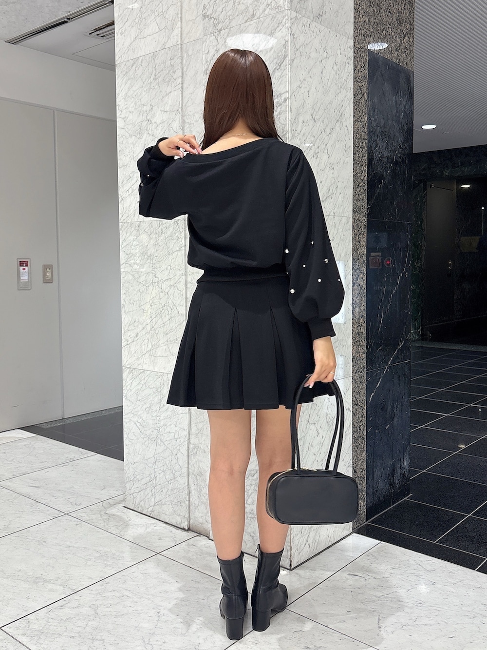 ブラック系のスカート、ブラック系のスウェット、ブラック系のブーツを着用したレディースの秋コーディネートの6枚目の写真