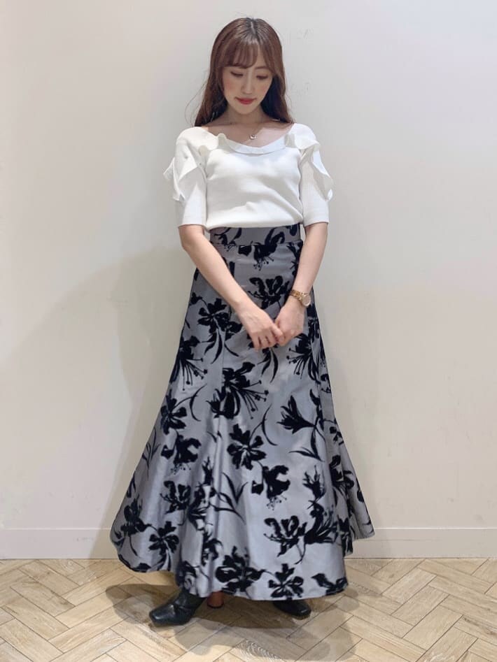 グレー系のスカート、ブラック系のサンダル、ホワイト系のニット/セーターを着用したレディースの夏コーディネートの2枚目の写真