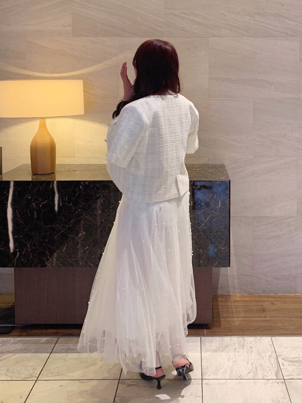 ホワイト系のスカート、ホワイト系のノーカラージャケット、ベージュ系のニット/セーターを着用したレディースの夏コーディネートの4枚目の写真