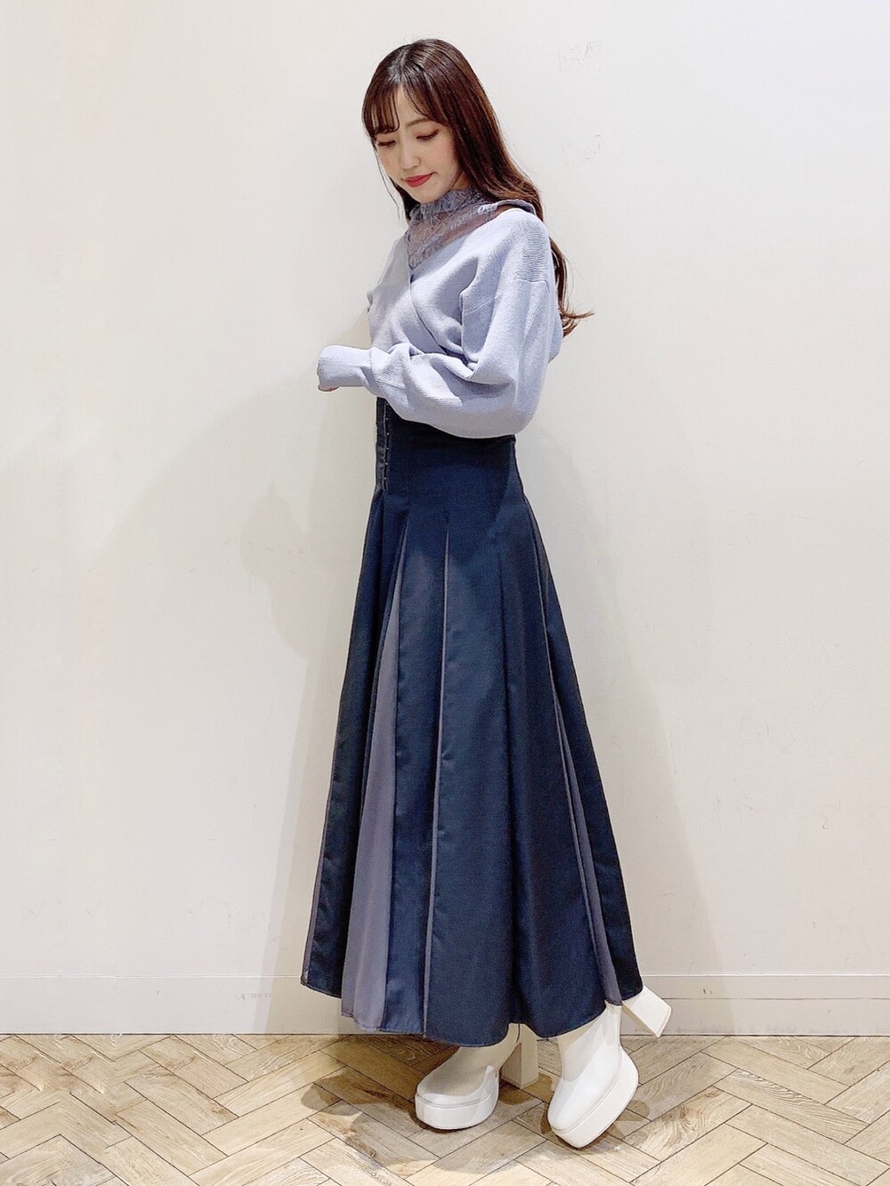 グレー系のスカート、ブルー系のニット/セーター、ホワイト系のブーツを着用したレディースの秋コーディネートの4枚目の写真