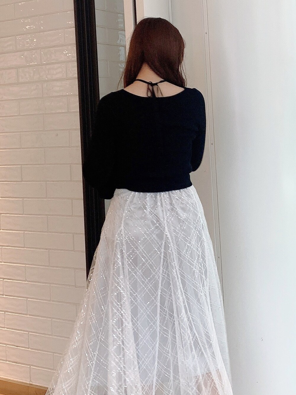 ブラック系のニット/セーター、グレー系のスカート、ホワイト系のパンプスを着用したレディースの冬コーディネートの7枚目の写真