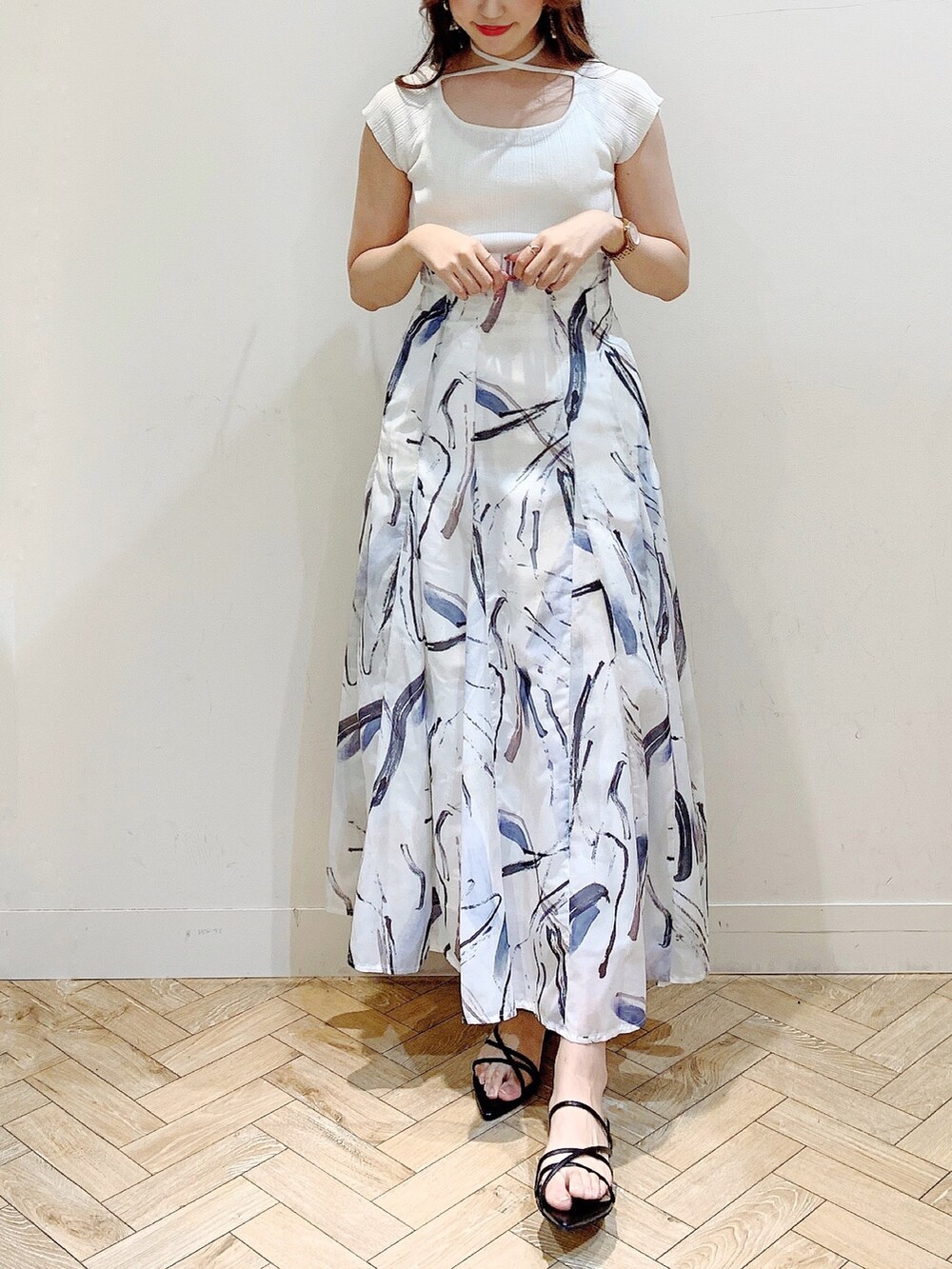 ホワイト系のニット/セーター、グレー系のスカート、ブラック系のサンダルを着用したレディースの夏コーディネートの3枚目の写真