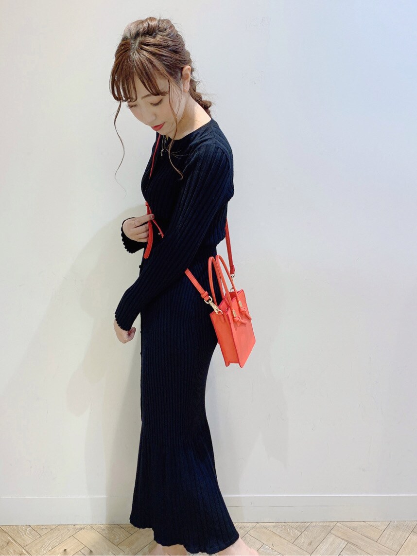 レッド系のハンドバッグ、ブラック系のスカート、グリーン系のサンダルを着用したレディースの春コーディネートの2枚目の写真