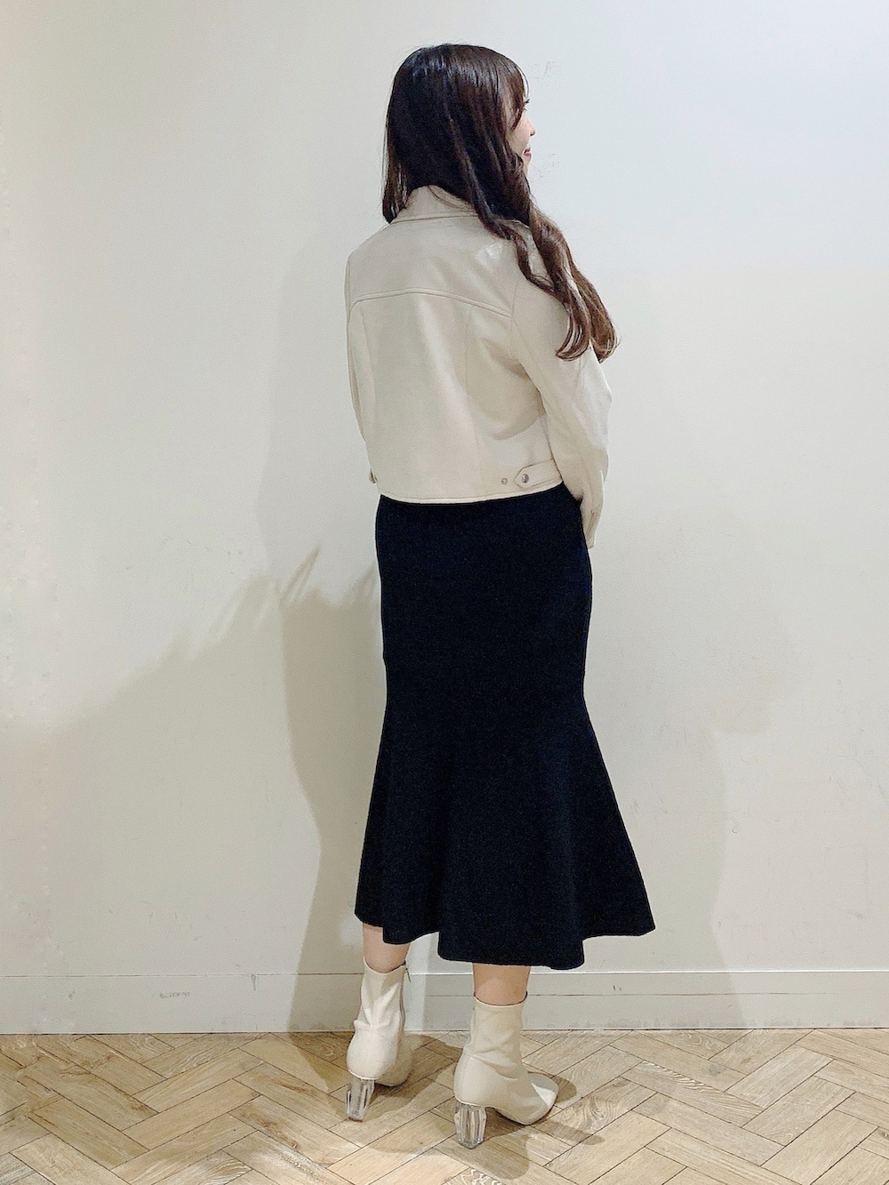 ブラック系のワンピース、ホワイト系のブーツ、ベージュ系のライダースジャケットを着用したレディースの冬コーディネートの7枚目の写真