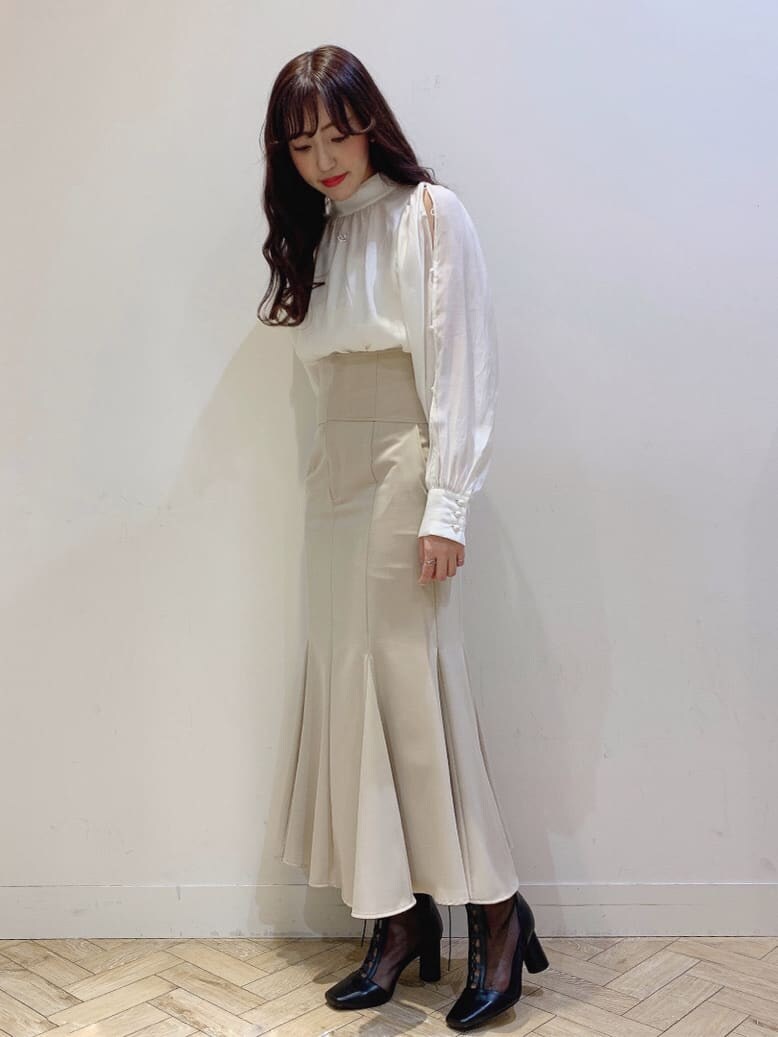 ベージュ系のスカート、ホワイト系のシャツ/ブラウスを着用したレディースの冬コーディネートの2枚目の写真