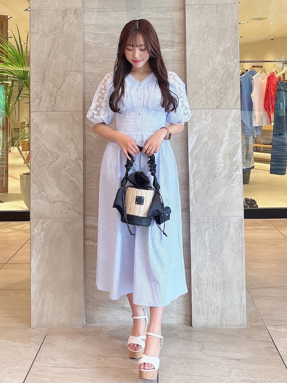ブラック系のかごバッグ、ホワイト系のサンダル、ブルー系のワンピースを着用したレディースの夏コーディネートの2枚目の写真