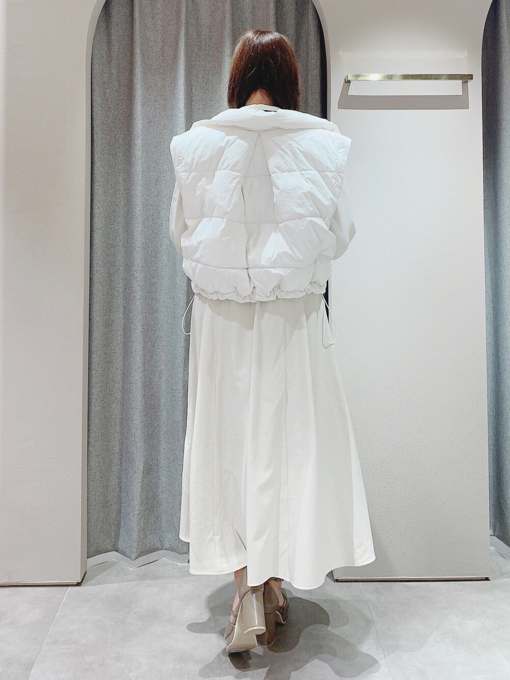 ベージュ系のパンプス、ホワイト系のワンピース、ホワイト系のダウンジャケット/コートを着用したレディースの秋コーディネートの8枚目の写真