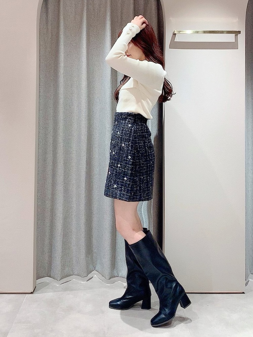 ブラック系のスカート、ブラック系のブーツ、ホワイト系のニット/セーターを着用したレディースの秋コーディネートの4枚目の写真