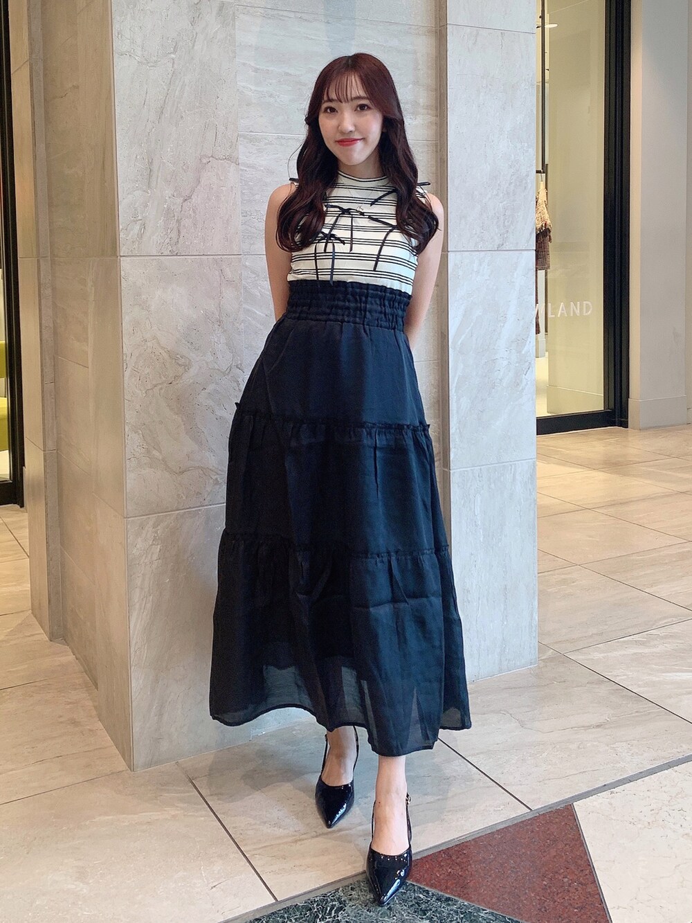 ブラック系のパンプス、ブラック系のワンピースを着用したレディースの夏コーディネートの2枚目の写真