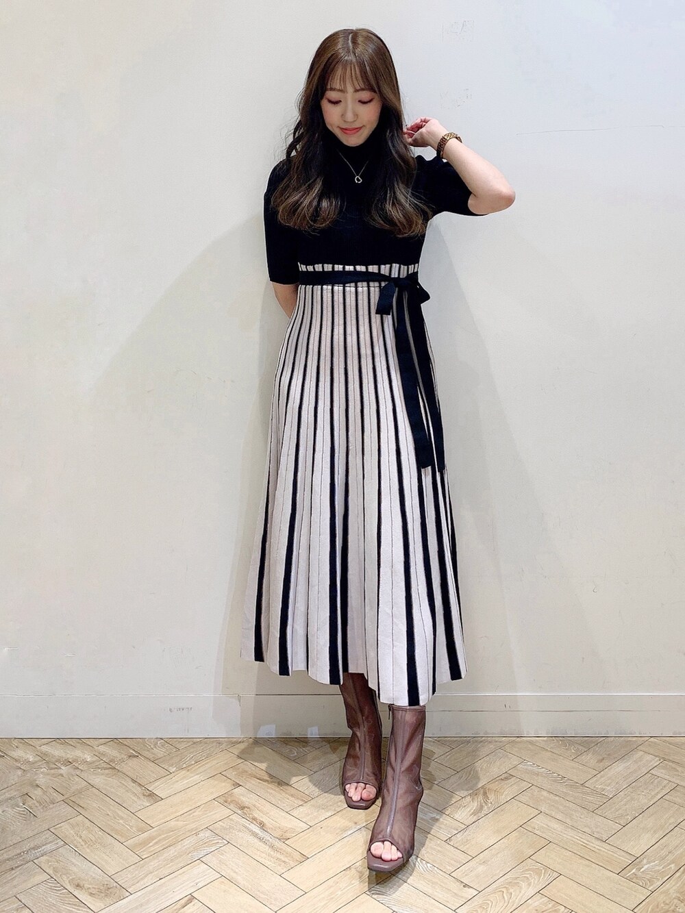 ブラック系のワンピース、ブラウン系のブーツを着用したレディースの春コーディネートの2枚目の写真