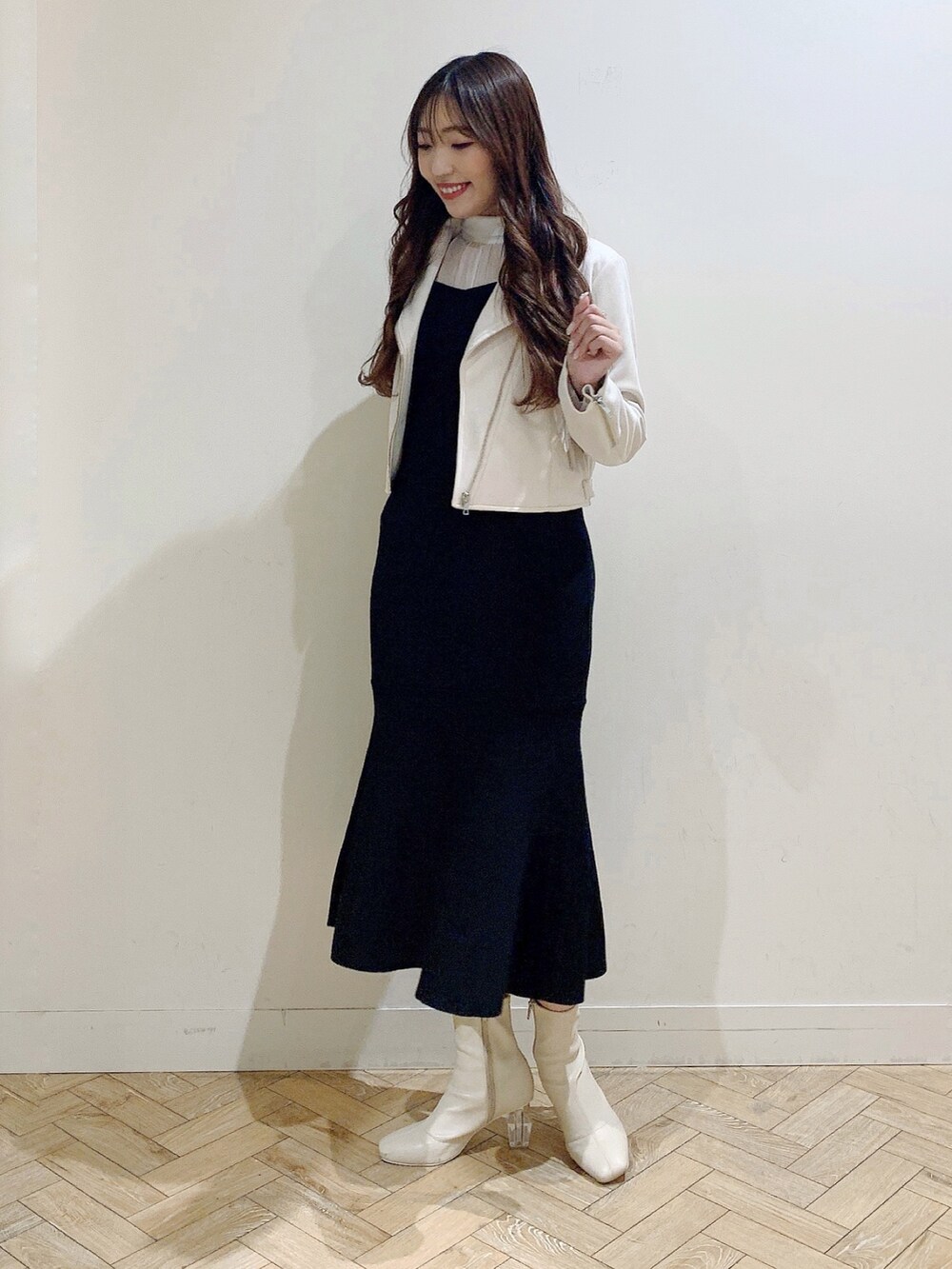 ブラック系のワンピース、ホワイト系のブーツ、ベージュ系のライダースジャケットを着用したレディースの冬コーディネートの3枚目の写真