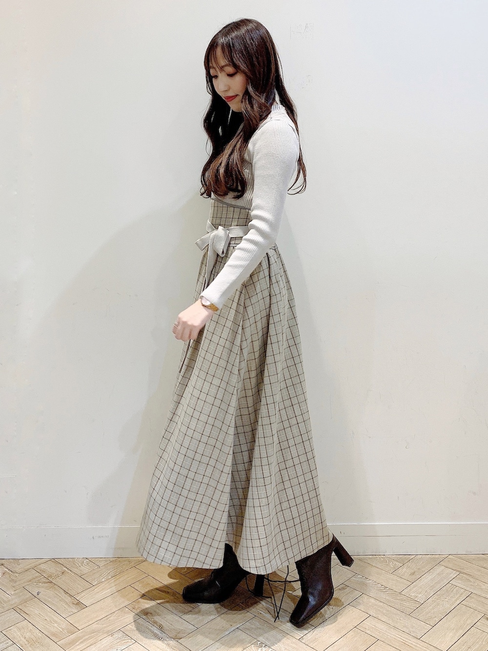 ブラウン系のチェスターコート、ブラウン系のブーツ、ベージュ系のワンピースを着用したレディースの冬コーディネートの3枚目の写真