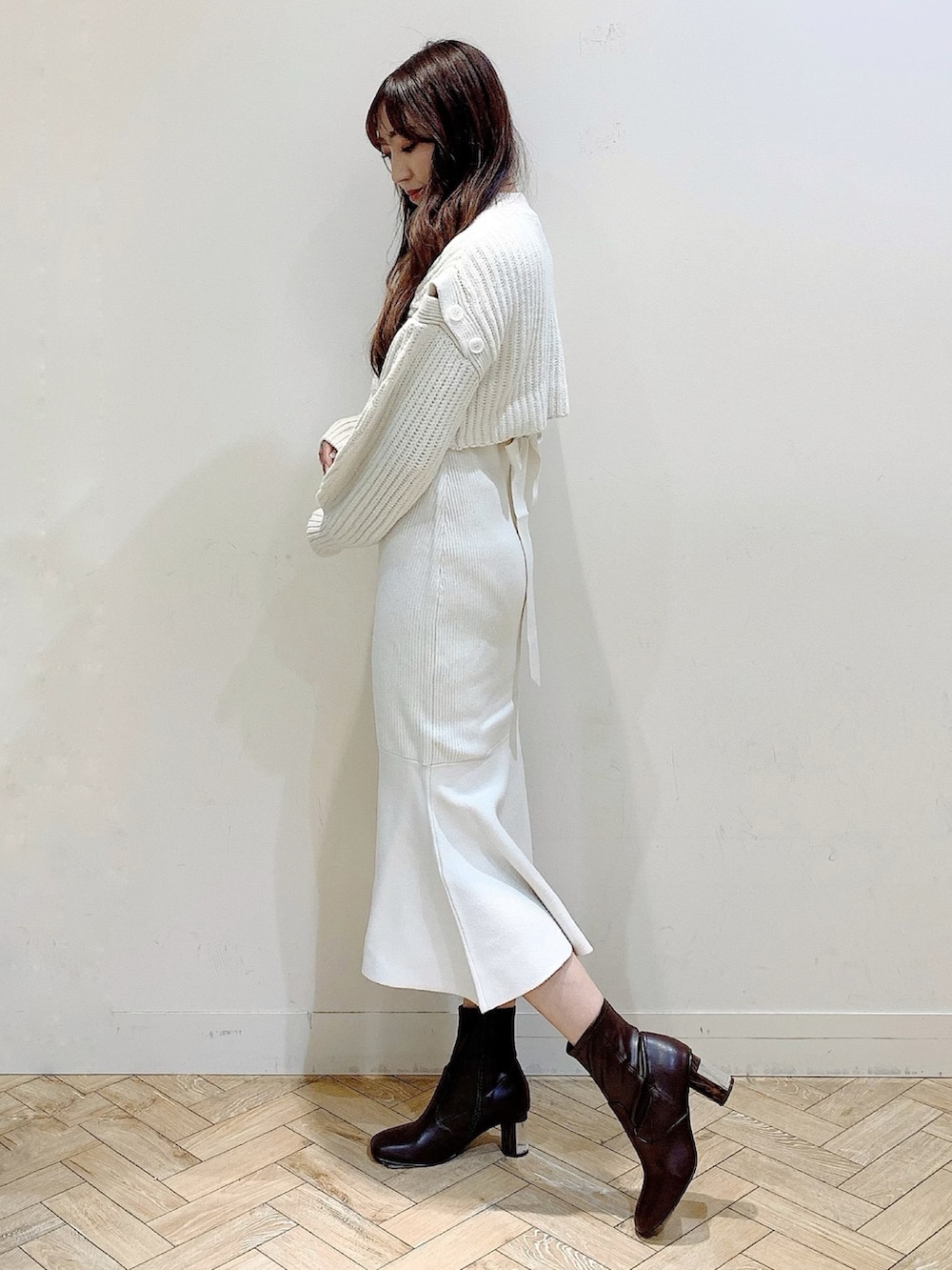 ホワイト系のワンピース、ベージュ系のステンカラーコート、ブラウン系のブーツを着用したレディースの冬コーディネートの3枚目の写真