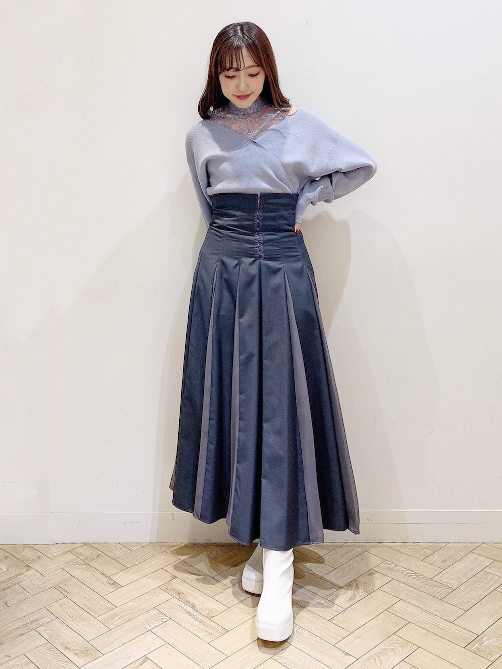 グレー系のスカート、ブルー系のニット/セーター、ホワイト系のブーツを着用したレディースの秋コーディネートの2枚目の写真