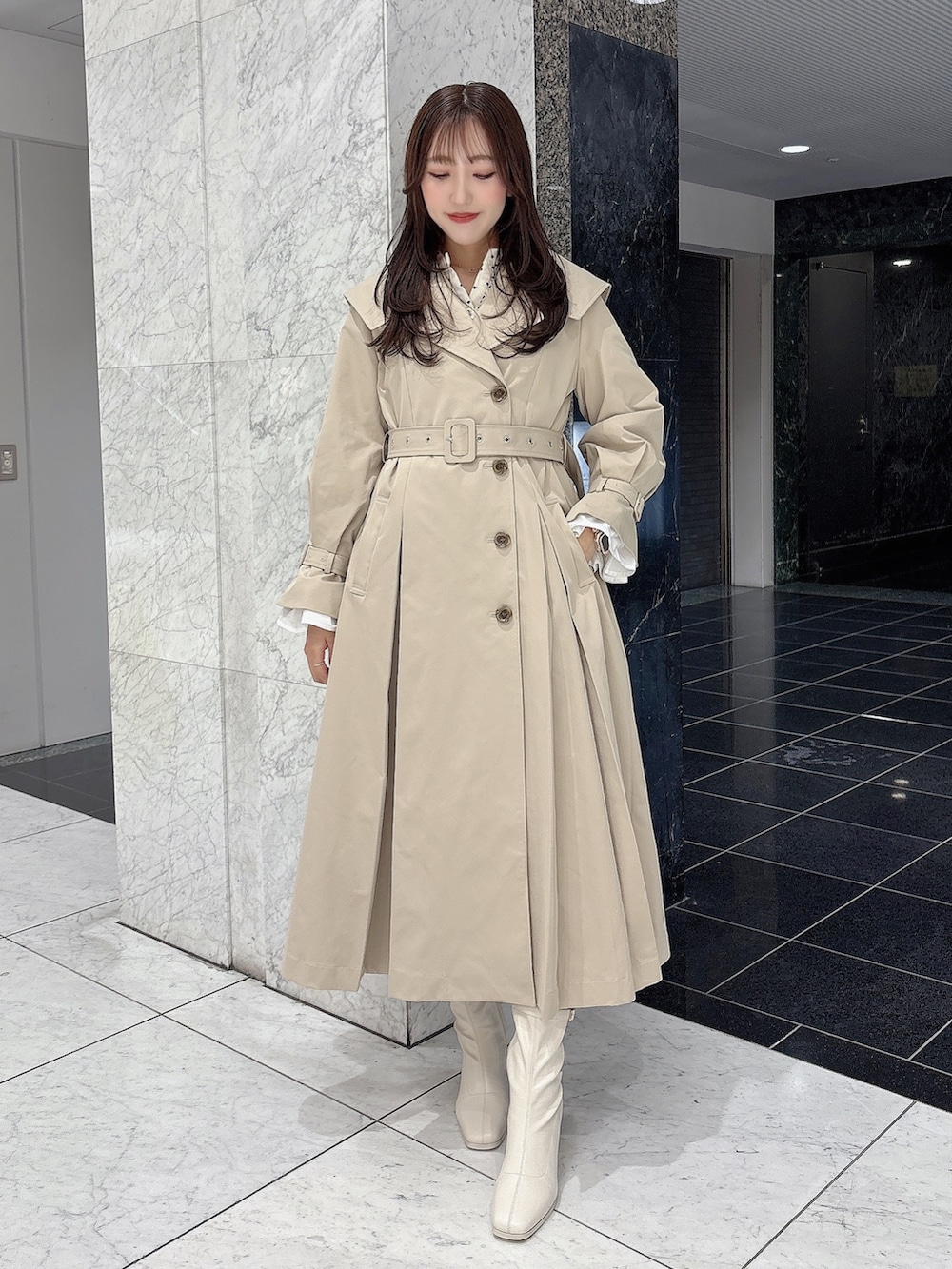 ホワイト系のブーツ、ベージュ系のトレンチコート、ホワイト系のワンピースを着用したレディースの冬コーディネートの2枚目の写真