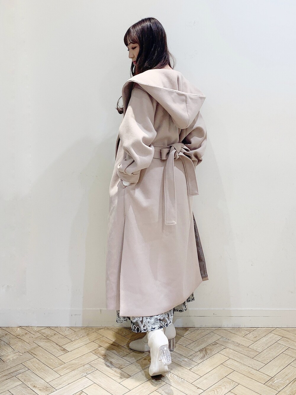 ブラック系のスカート、ホワイト系のニット/セーター、ベージュ系のチェスターコートを着用したレディースの冬コーディネートの3枚目の写真