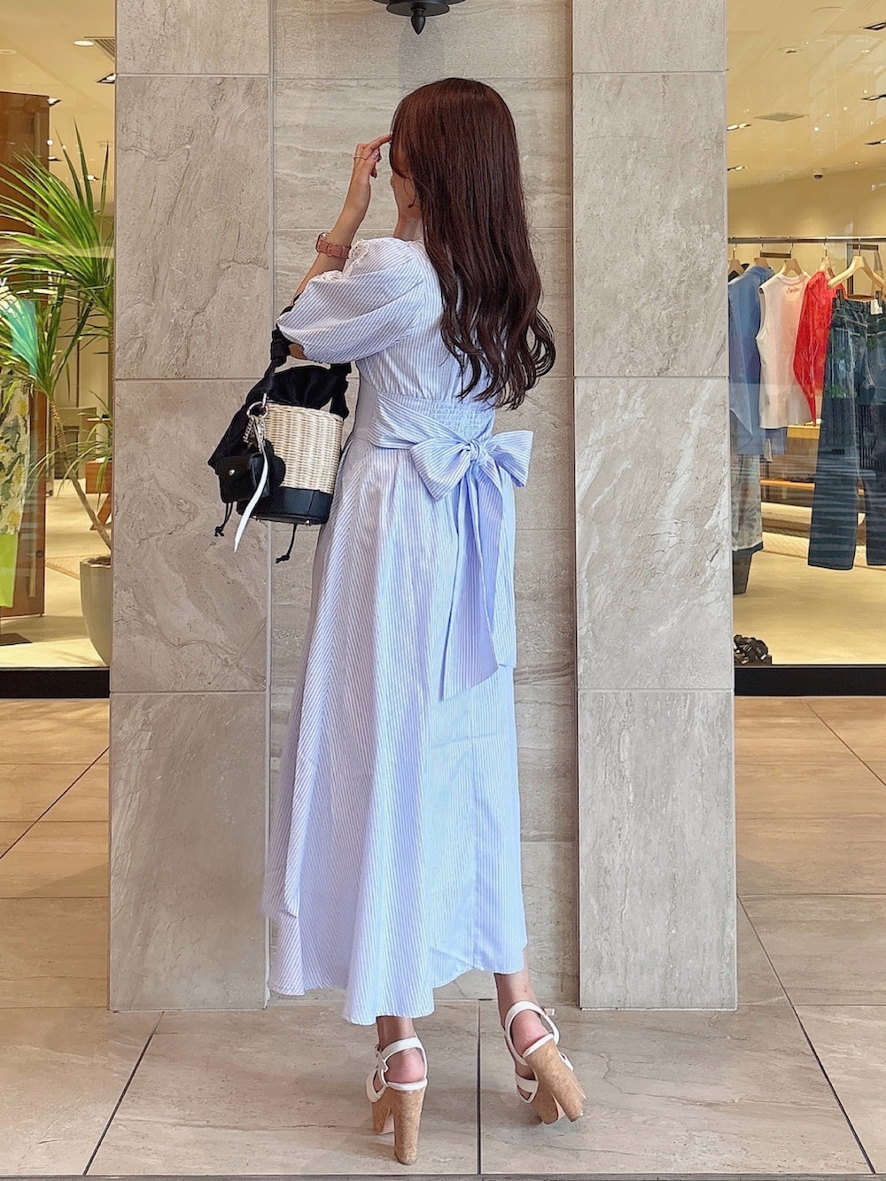 ブラック系のかごバッグ、ホワイト系のサンダル、ブルー系のワンピースを着用したレディースの夏コーディネートの4枚目の写真