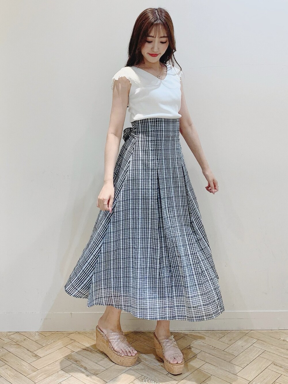 ブラック系のスカート、ホワイト系のニット/セーターを着用したレディースの夏コーディネートの2枚目の写真