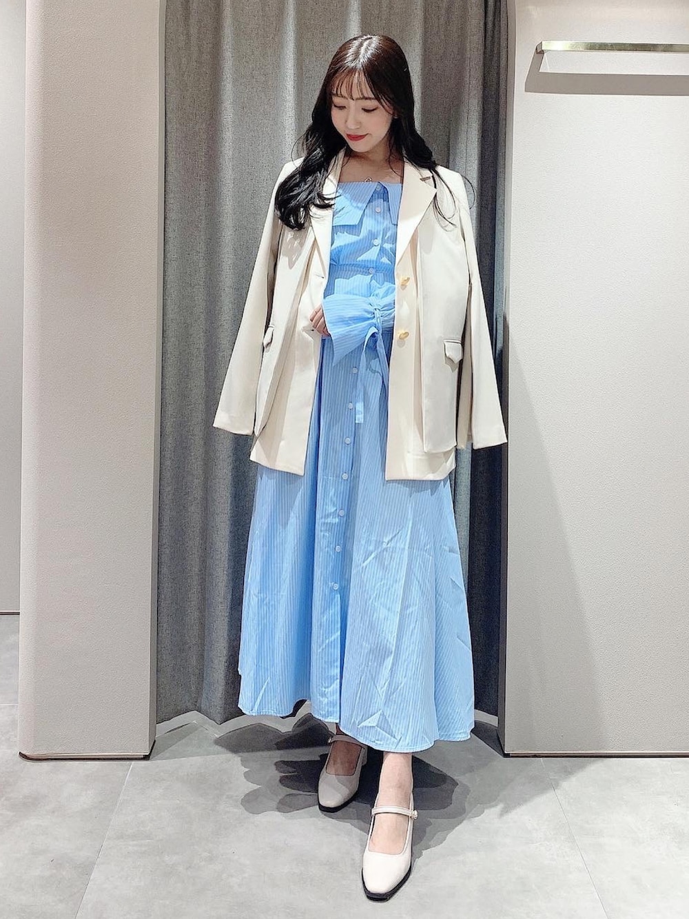ブルー系のシャツワンピース、ホワイト系のテーラードジャケット、ホワイト系のパンプスを着用したレディースの冬コーディネートの7枚目の写真
