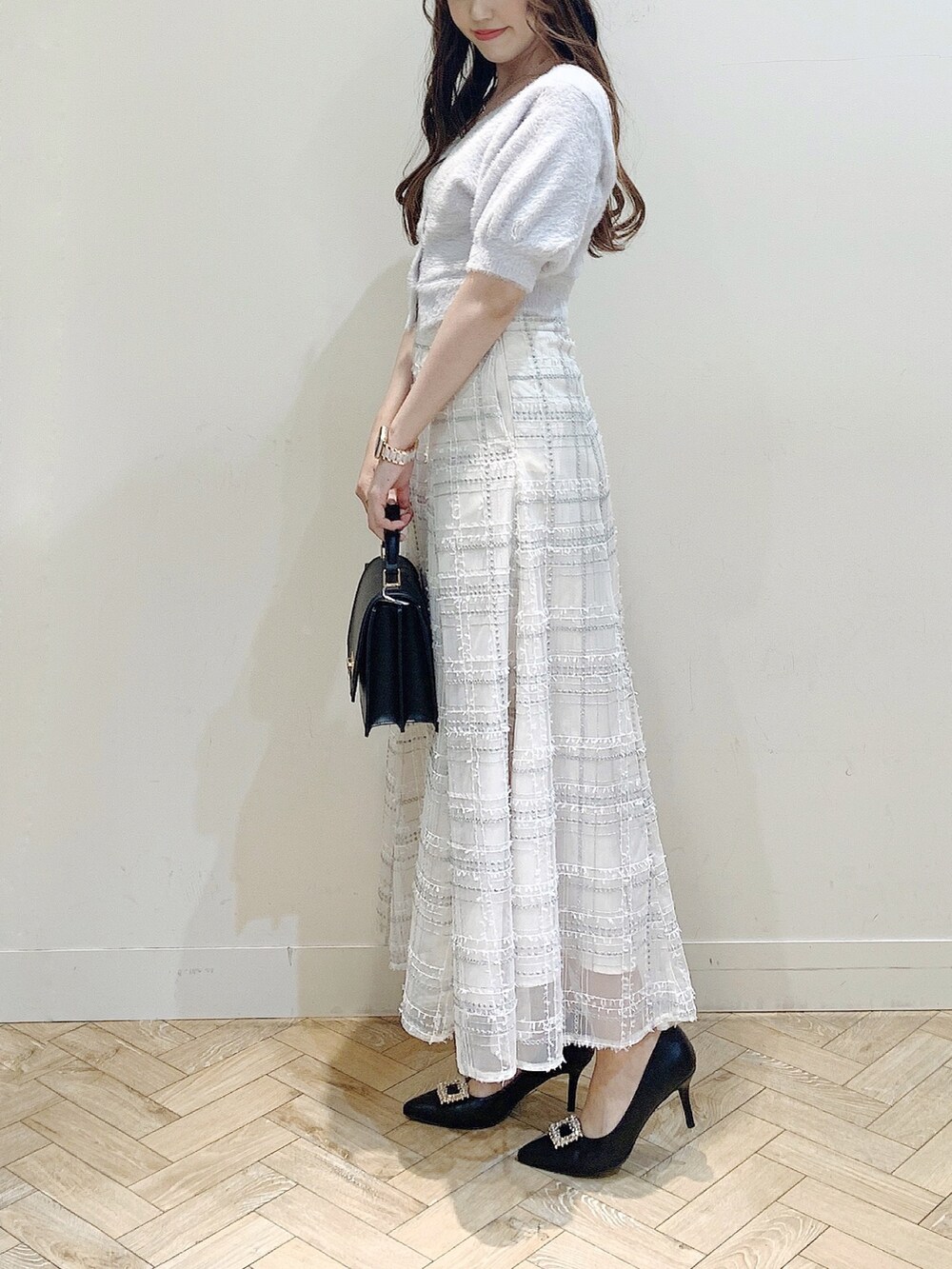 パープル系のカーディガン/ボレロ、ブラック系のスカート、ブラック系のパンプスを着用したレディースの夏コーディネートの5枚目の写真