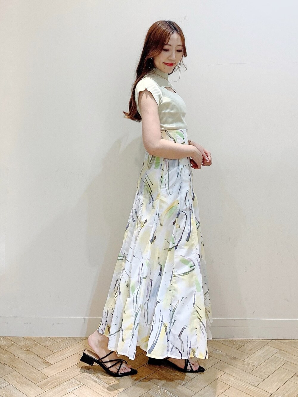 グリーン系のニット/セーター、イエロー系のスカート、ブラック系のサンダルを着用したレディースの夏コーディネートの5枚目の写真