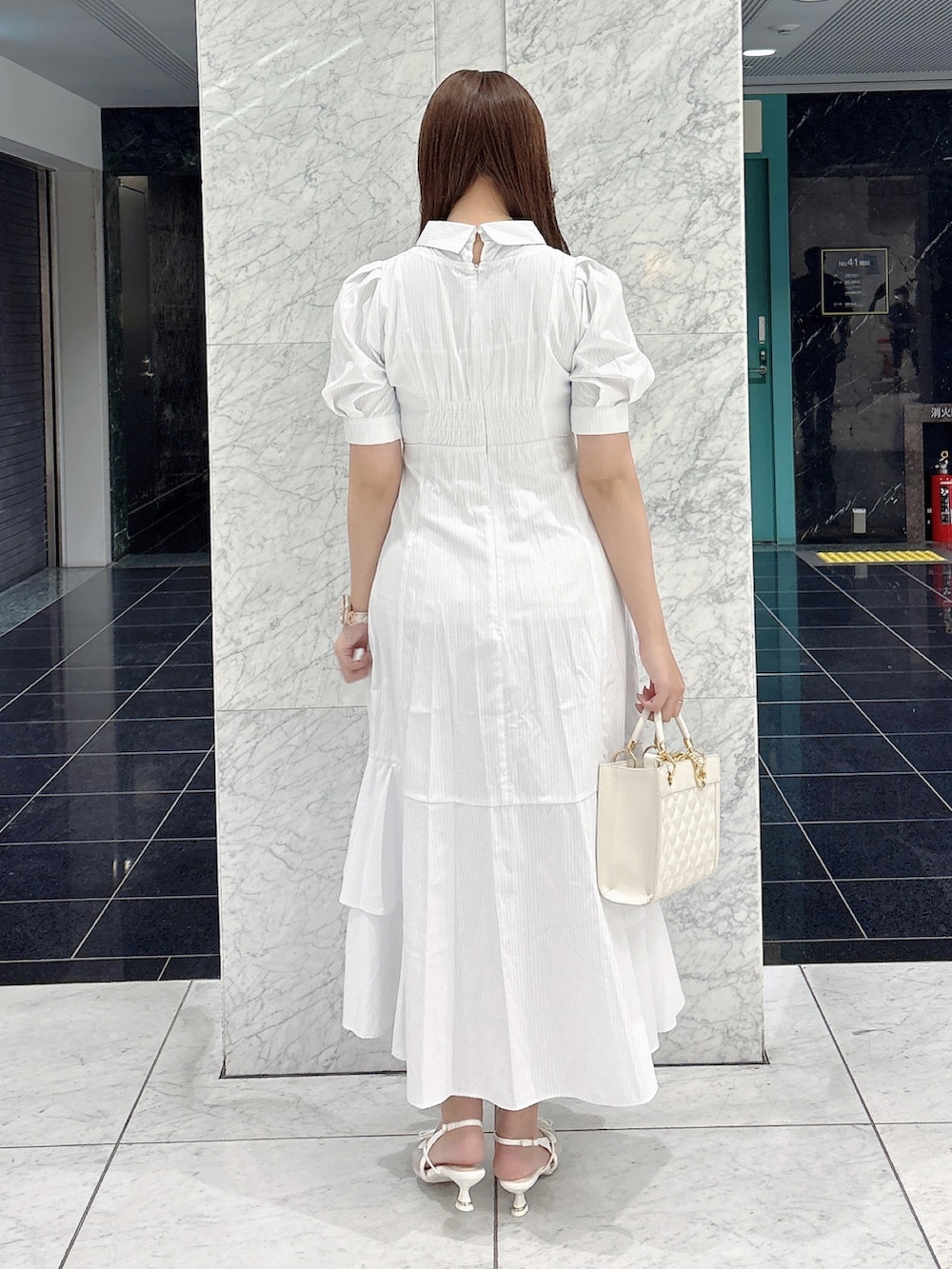 ホワイト系のワンピース、ホワイト系のパンプス、ホワイト系のハンドバッグを着用したレディースの春コーディネートの7枚目の写真