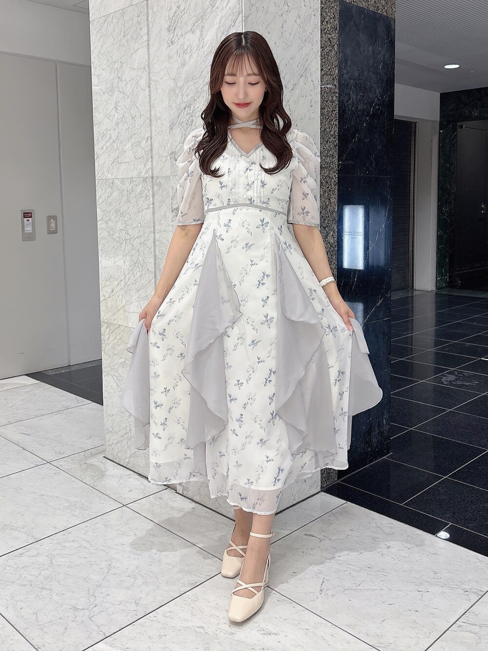 ホワイト系のサンダル、ホワイト系のワンピース、ベージュ系のトレンチコートを着用したレディースの春コーディネートの2枚目の写真