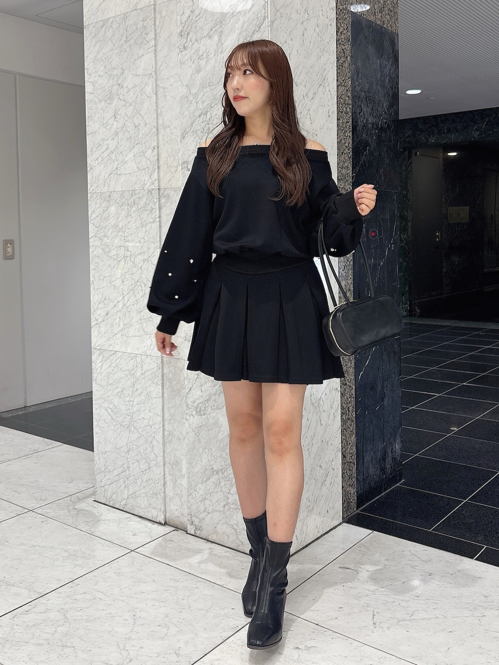 ブラック系のスカート、ブラック系のスウェット、ブラック系のブーツを着用したレディースの秋コーディネートの4枚目の写真