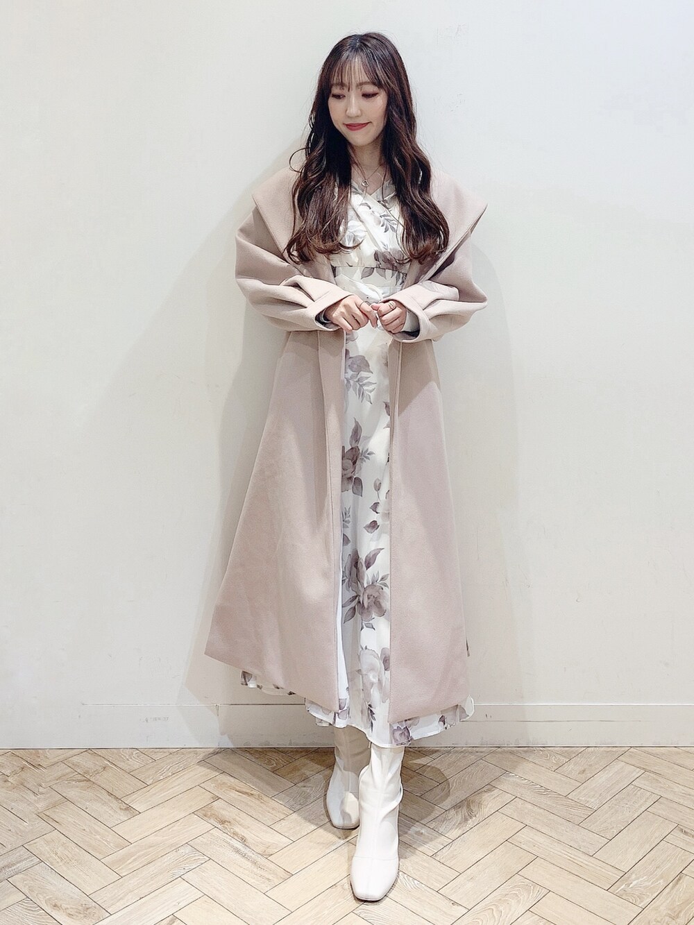 ベージュ系のチェスターコート、ホワイト系のワンピース、ホワイト系のブーツを着用したレディースの冬コーディネートの2枚目の写真