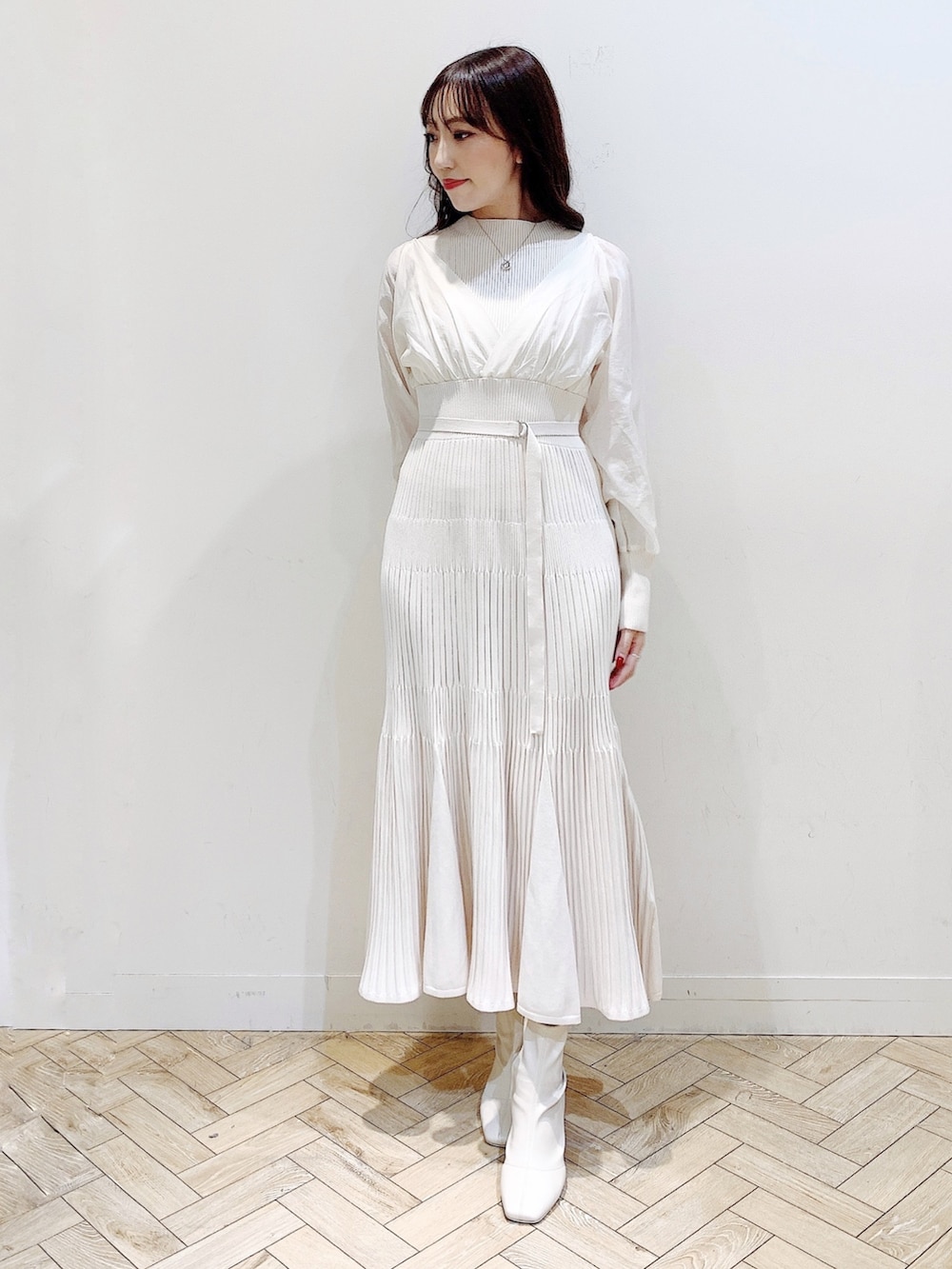 ホワイト系のワンピース、ブラウン系のチェスターコート、ホワイト系のブーツを着用したレディースの冬コーディネートの4枚目の写真