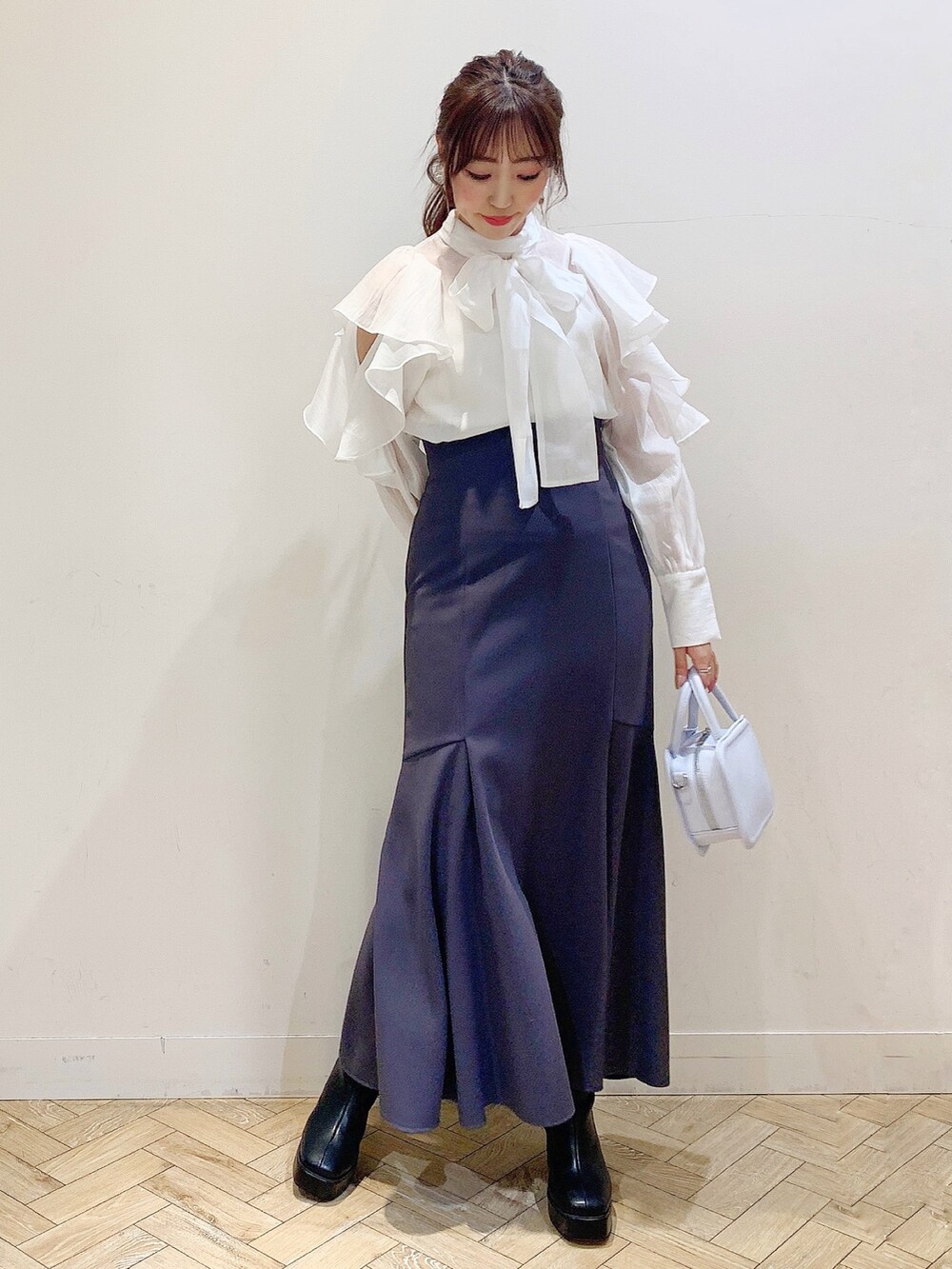 ホワイト系のシャツ/ブラウス、グレー系のスカート、ブルー系のハンドバッグを着用したレディースの冬コーディネートの3枚目の写真