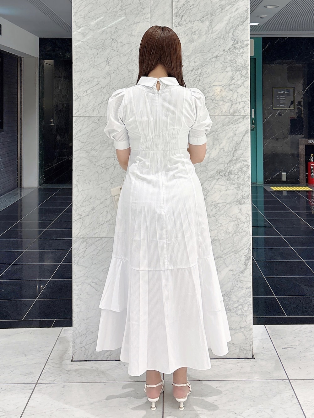 ホワイト系のワンピース、ホワイト系のパンプス、ホワイト系のハンドバッグを着用したレディースの春コーディネートの6枚目の写真