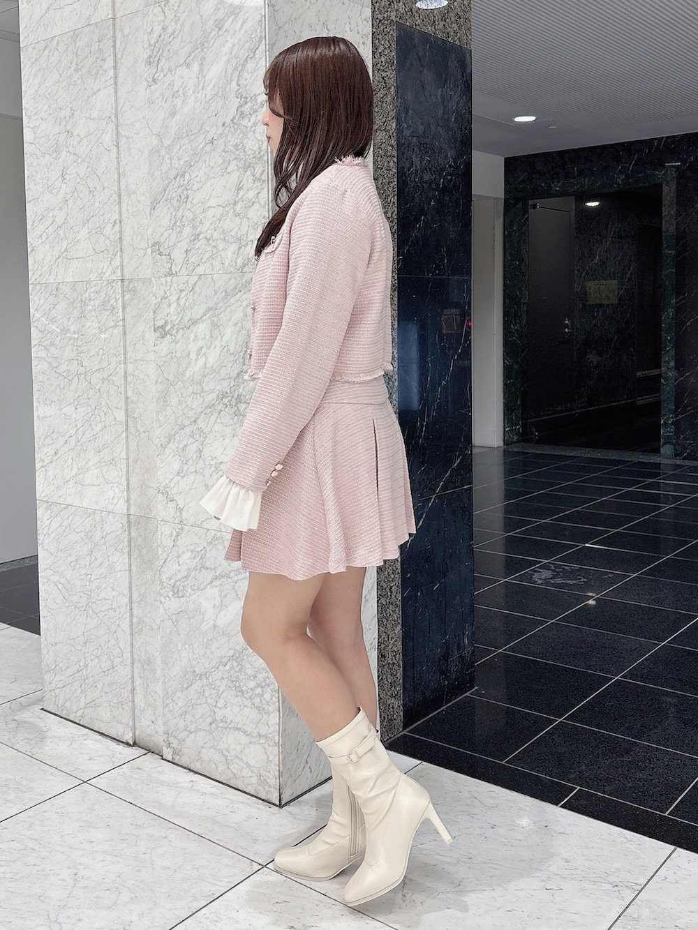 ピンク系のノーカラージャケット、ピンク系のスカート、ホワイト系のブーツを着用したレディースの冬コーディネートの3枚目の写真