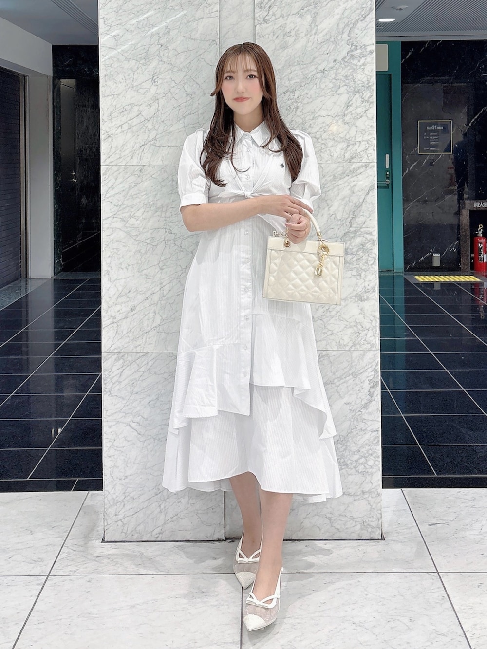 ホワイト系のワンピース、ホワイト系のパンプス、ホワイト系のハンドバッグを着用したレディースの春コーディネートの2枚目の写真