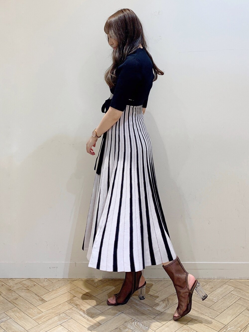 ブラック系のワンピース、ブラウン系のブーツを着用したレディースの春コーディネートの6枚目の写真